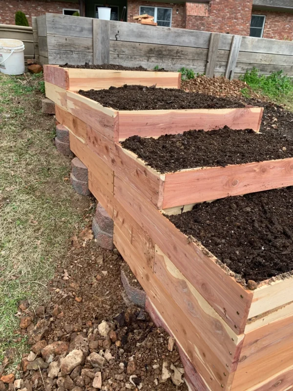 A wooden planter with dirt on top of it.