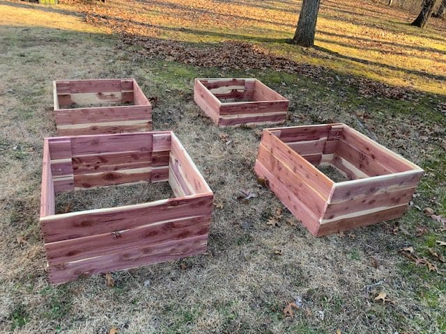 A group of three wooden boxes sitting in the grass.