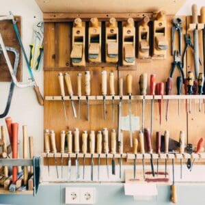 A wall of tools hanging on the side of a room.