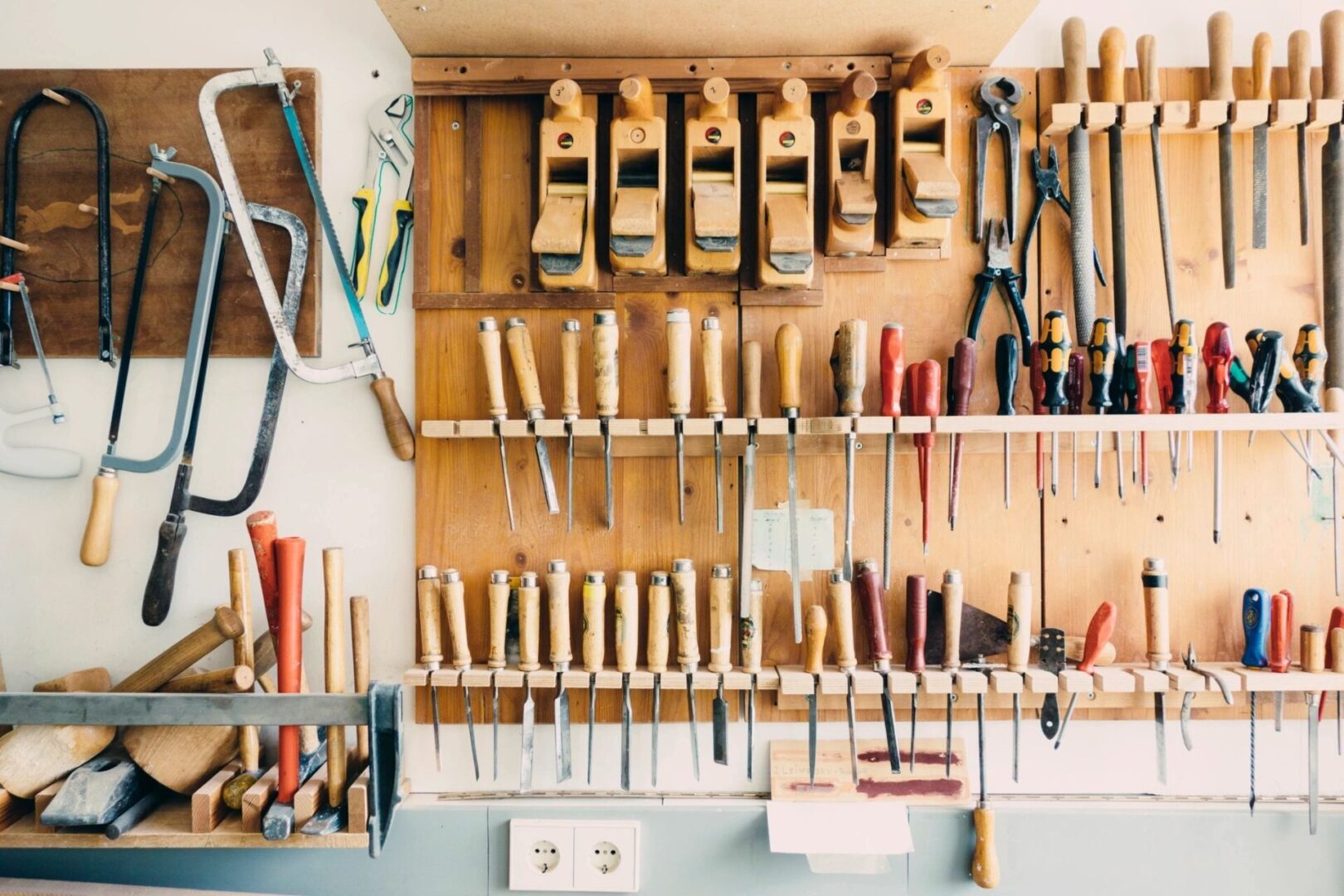 A wall of tools hanging on the side of a room.